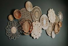 decorative wall hangings made out of wicker and paper doilies on a gray wall