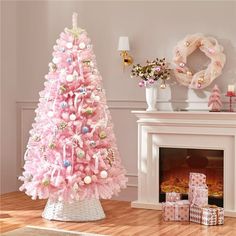 a pink christmas tree in a living room with presents on the floor next to it