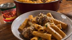 pasta with meatballs and parmesan cheese in a bowl next to a can of macaroni and cheese