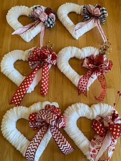 four heart shaped wreaths are arranged on the floor with ribbons and bows around them