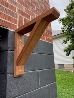 a wooden shelf on the side of a brick building with grass in front of it