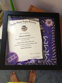 a person standing in front of a framed certificate with their feet propped up on the floor