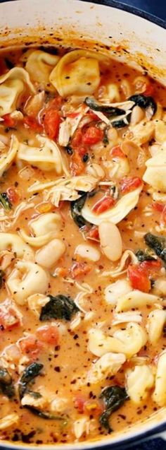 pasta and spinach soup in a pot on a blue tablecloth with utensils