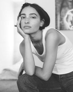 a black and white photo of a woman sitting on the floor with her hand under her face