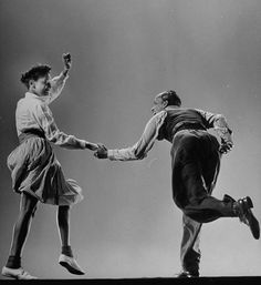 an old photo of two people dancing on stage with one holding the other's hand