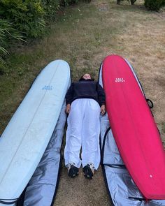 a man laying on the ground with three surfboards next to him and his head resting on one another