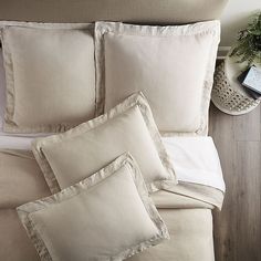 a bed with four pillows on top of it next to a night stand and phone