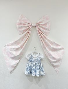 two bows hang on the wall next to a baby's dress