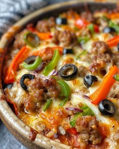 a close up of a pizza with peppers, olives, and meat on it