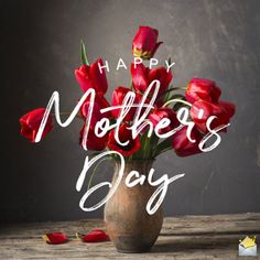 a vase filled with red tulips on top of a wooden table