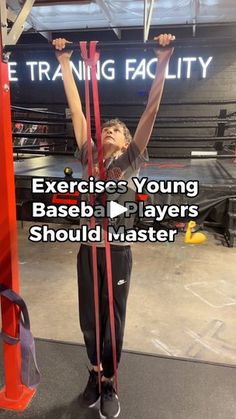 a man is doing exercises in the gym with his hands up and holding two red barbells