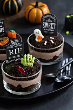 three desserts decorated with halloween decorations on a black plate