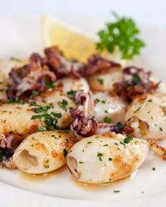 a white plate topped with shells covered in sauce and garnished with parsley