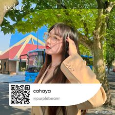 a woman with long hair and glasses is standing in front of a tree while talking on her cell phone