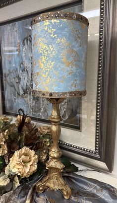 a blue and gold lamp sitting on top of a table next to a framed mirror