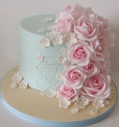 a blue and white cake with pink roses on top