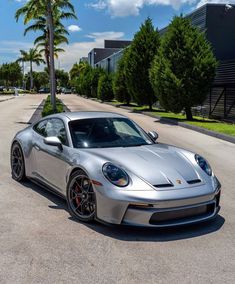 a silver sports car parked on the side of a road in front of palm trees