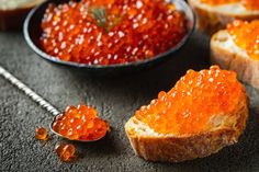 several pieces of bread with red cavia on them next to a bowl of orange cavia