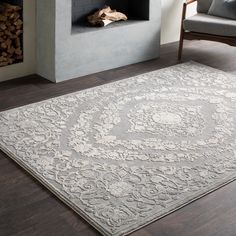 a large rug with an intricate design on the floor in front of a fire place