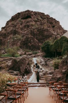 a bride and groom standing at the end of their wedding ceremony in front of a mountain