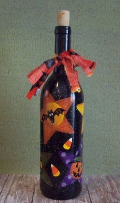 a bottle that has been decorated with halloween images and pumpkins on it, sitting on a wooden table