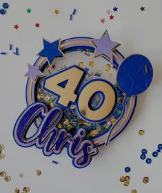 a blue and gold birthday cake with the number 40 on it, surrounded by confetti