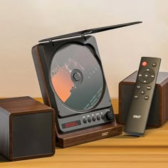 an old fashioned television and remote control sitting on a wooden table next to two speakers