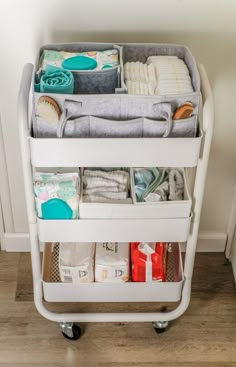 a white cart filled with diapers and other items on top of a wooden floor