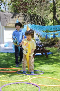 two children are standing in the grass with some rings around them and one boy is wearing a yellow shirt