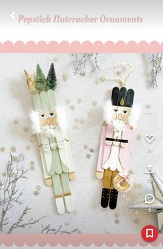 two wooden nutcracker ornaments sitting next to each other on a white background with snowflakes