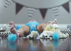 a baby laying on its back in front of a cake