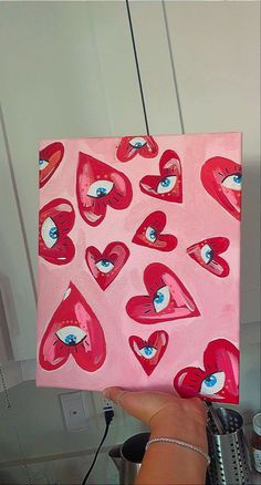 a person holding up a painting with hearts on it