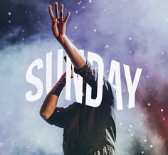 a man holding his hands up in the air while standing on top of a stage