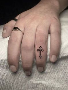 a woman's hand with a small cross tattoo on her left thumb and ring finger