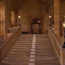 an old building with stairs and lamps on either side of the entrance way, leading up to the second floor