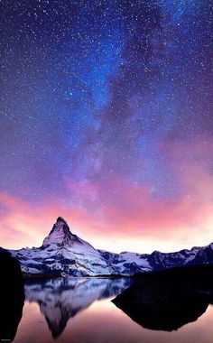 the night sky is filled with stars above a mountain and body of water in front of it