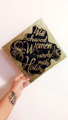 a woman's hand holding up a gold graduation cap with writing on the side