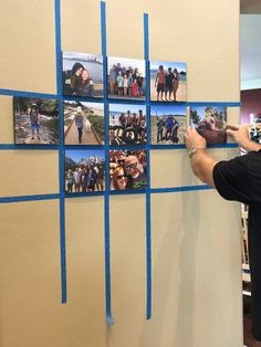 a man is taking pictures on a wall with his cell phone and some blue tape