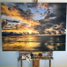 an easel is sitting in front of a painting on the wall with clouds above it