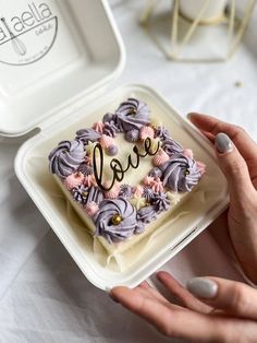 a person holding up a cake with the word love on it in front of them