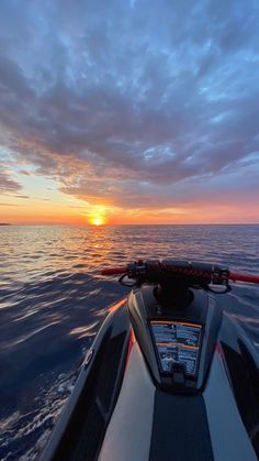 the sun is setting over the ocean as seen from a speed boat in the water