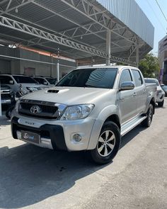 a silver toyota truck parked in front of a building next to other cars on the street