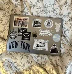 an apple laptop covered in stickers on a bed