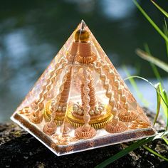 a triangle shaped glass object sitting on top of a rock