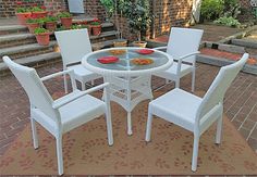 a white table and chairs sitting on top of a brown rug in front of a brick building