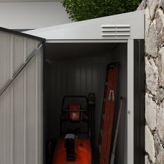 an orange fire extinguisher sitting in the back of a storage shed next to a brick wall