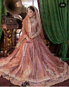 a woman sitting in front of a piano wearing a pink and gold bridal gown