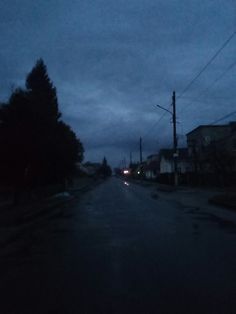 an empty street at night with no cars on the road and dark clouds in the sky