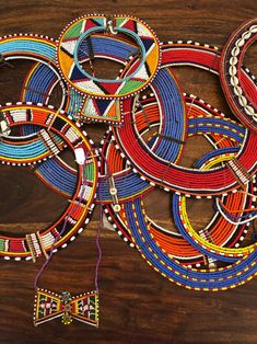 an assortment of colorful beaded items on a wooden surface with a bow tie hanging from it