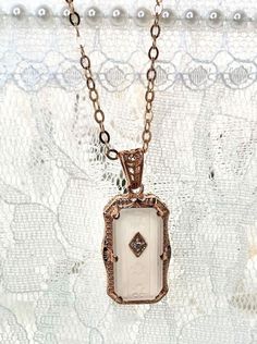 Camphor Glass Rose Gold plated Sterling Silver Pendant Necklace 1915 Design#P232 This is an Art Deco inspired pendant necklace. This gorgeous pendant is set with stunning carved floral white frosted camphor glass and has a 1mm white cubic zirconia (CZ) accent. The camphor glass pendant is 29mm long by 13mm wide (including the bail). The setting is a recasting of a brooch from the Art Deco 1930's era. The chain (if chosen) is adjustable from 18" to 20". The pendant and chain are solid sterling si Antique Silver Etched Pendant Necklace, Antique Etched Pendant Locket Necklace, Camphor Glass Jewelry Ring, Camphor Glass Jewelry, Collectible Art Deco Locket Necklace, Glass Rose, Floral White, Sterling Silver Necklace Pendants, Rose Gold Jewelry